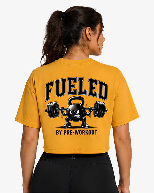 Vista traseira da Crop T-Shirt Fueled by Pre-Workout em Mustard, com grafismo de kettlebell e barra carregada nas costas.