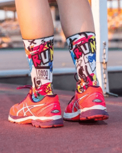 Atleta com Meias Hybrid Happy Run da Monolon com cano alto e grafismo colorido inspirado no running, com elementos e frases relacionados com corrida.
