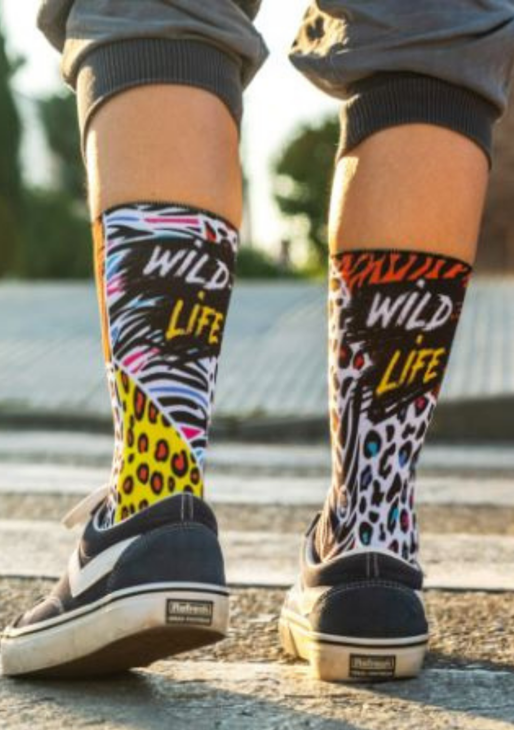 Pessoa com  meias wild llife com cano alto e grafismo multicolor inspirado em padrões de zebra, tigre e leopardo.