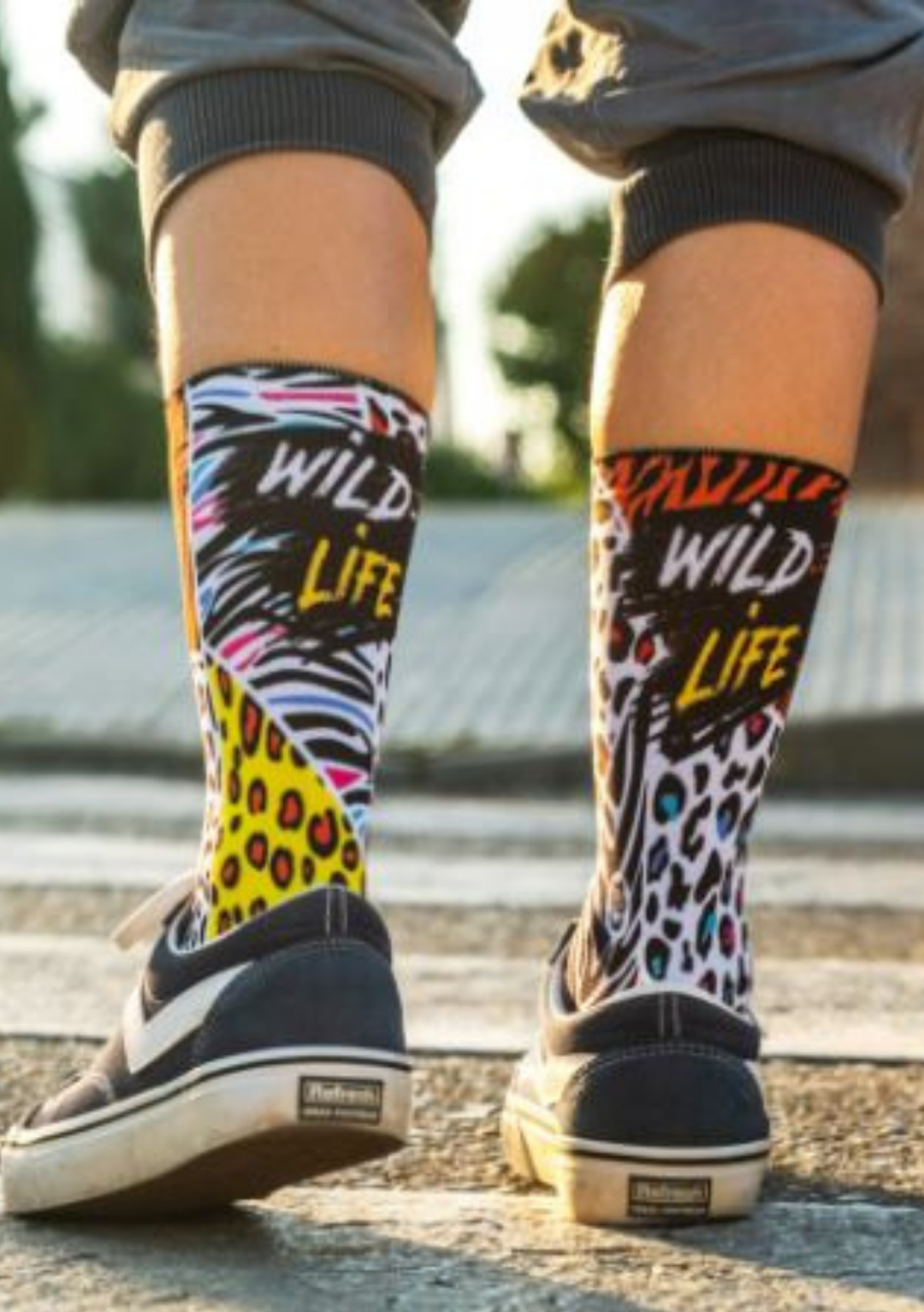 Pessoa com  meias wild llife com cano alto e grafismo multicolor inspirado em padrões de zebra, tigre e leopardo.