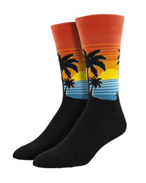 Meias Find Your Beach - Lifestyle da Socksmith em preto, com paisagem tropical de palmeiras, mar e pôr do sol em tons quentes.