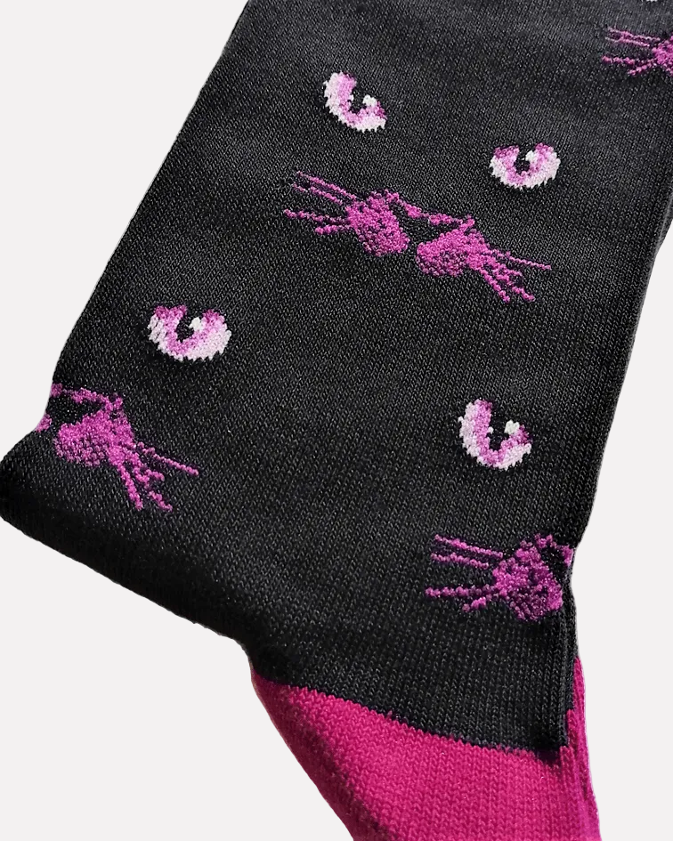 detalhe Meias Eyeing You - Lifestyle da Socksmith em preto, com padrão de olhos e bigodes de gato e detalhes em roxo.