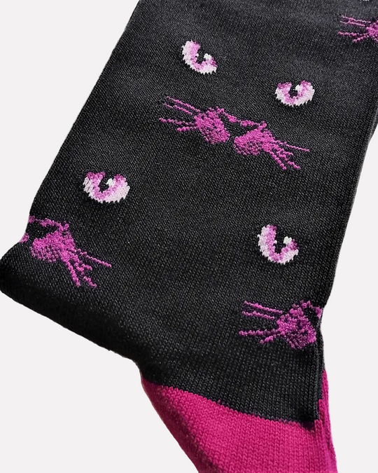 detalhe Meias Eyeing You - Lifestyle da Socksmith em preto, com padrão de olhos e bigodes de gato e detalhes em roxo.